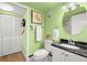 Well-lit bathroom featuring green walls, modern sink, toilet, white towels and a closet at 80 Rogers St # 3A, Clearwater, FL 33756