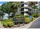 Property signage surrounded by manicured, tropical landscaping on a sunny day with water views at 80 Rogers St # 3A, Clearwater, FL 33756