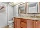 Bathroom showcasing a double sink vanity with granite countertops, tiled floors, and a toilet at 8005 Pepperidge Ln, Port Richey, FL 34668