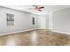Spacious bedroom featuring neutral walls, tiled floor, ceiling fan, and natural light from two windows at 8005 Pepperidge Ln, Port Richey, FL 34668