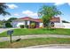 Charming home featuring green lawn, red roof, two-car garage, and mature landscaping and a mailbox on a sunny day at 8005 Pepperidge Ln, Port Richey, FL 34668