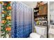 Bathroom with a decorative shower curtain, open shelving, and commode at 8502 N Hyaleah Rd, Tampa, FL 33617