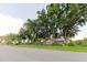 Exterior view of a single-story home with mature trees and a fenced yard, photographed from the street at 11109 Sumner Rd, Wimauma, FL 33598