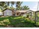 Exterior view of a home with a metal roof and car port, surrounded by a fenced yard and trees at 11109 Sumner Rd, Wimauma, FL 33598