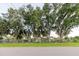 Exterior view of a single-story home with mature trees and a fenced yard, captured from the street at 11109 Sumner Rd, Wimauma, FL 33598