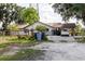 Exterior view of a single-story home with a metal roof, fenced yard, car port and mature trees at 11109 Sumner Rd, Wimauma, FL 33598