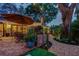 Charming back patio with brickwork, stone pathway, dining set, and landscape lighting for evening ambiance at 11760 Ashley Ct, Seminole, FL 33772
