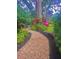 Lush backyard with mulched path, mature trees, and a pink flamingo at 11760 Ashley Ct, Seminole, FL 33772
