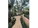 Lush backyard oasis with stone pathway, manicured landscaping, and serene seating area with pink flamingos at 11760 Ashley Ct, Seminole, FL 33772