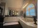 Bright bathroom with soaking tub, white cabinets, and arched window with plantation shutters at 11760 Ashley Ct, Seminole, FL 33772