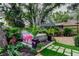 Backyard featuring a hot tub with surrounding lush landscaping and flamingo decor at 11760 Ashley Ct, Seminole, FL 33772