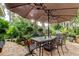 Charming outdoor patio featuring a dining set under a large umbrella, surrounded by lush landscaping at 11760 Ashley Ct, Seminole, FL 33772