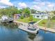 Waterfront home with a private dock and pontoon boat, alongside a well-maintained lawn and neatly trimmed greenery at 13316 Carol Dr, Hudson, FL 34667