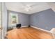 Serene bedroom with hardwood floors, a ceiling fan, and a large window with natural light at 15612 Farnsworth Ln, Tampa, FL 33624