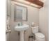 Cozy half bathroom featuring a pedestal sink, toilet, and a decorative mirror, perfect for guests at 15612 Farnsworth Ln, Tampa, FL 33624