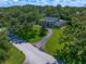 Aerial view of a home with a circular driveway surrounded by lush greenery on a partly cloudy day at 1681 Long Bow Ln, Clearwater, FL 33764