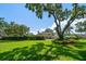 View of the spacious backyard featuring a large tree and lush green lawn with a backyard patio at 1681 Long Bow Ln, Clearwater, FL 33764