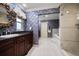 Bathroom featuring a granite-topped vanity, floral wallpaper, and a separate tub and shower area at 1681 Long Bow Ln, Clearwater, FL 33764