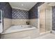 A soaking tub with travertine tile and shower is set against floral wallpaper at 1681 Long Bow Ln, Clearwater, FL 33764