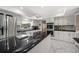 Modern eat-in kitchen equipped with stainless steel appliances, black countertops, and white marble tile flooring at 1681 Long Bow Ln, Clearwater, FL 33764