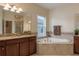 Relaxing bathroom features a soaking tub, glass-enclosed shower, and dual vanities with granite counters at 19309 Prairie Tree Pl, Tampa, FL 33647