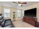 Carpeted living room with a ceiling fan, large flat-screen TV, and display cabinet at 19309 Prairie Tree Pl, Tampa, FL 33647