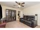 Living room with black leather reclining sofa, ceiling fan, and display cabinets at 19309 Prairie Tree Pl, Tampa, FL 33647