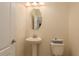 Modern powder room featuring a white pedestal sink, toilet, and natural light from a small window at 19309 Prairie Tree Pl, Tampa, FL 33647