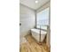 Bright bathroom features a modern freestanding tub, wood-look tile flooring, and stone-tiled shower at 27312 Edenfield Dr, Wesley Chapel, FL 33544