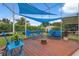 Inviting patio area with blue furniture, wooden decking, blue shade, and well-maintained landscaping at 40449 Trotter Ln, Dade City, FL 33525