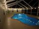 Charming pool area featuring a serene in-ground pool with screened enclosure, illuminated by string lights at 40449 Trotter Ln, Dade City, FL 33525