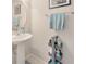 A well-lit half bathroom with a pedestal sink, decorative towels, and gray wicker baskets at 4703 Somerset Hill Ln, Riverview, FL 33578