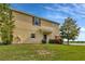 Inviting tan two-story townhome with a well-maintained lawn, enhanced by mature trees and landscaping at 4703 Somerset Hill Ln, Riverview, FL 33578
