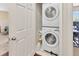 A laundry room with stacked washer and dryer adjacent to the carpeted main bedroom at 4703 Somerset Hill Ln, Riverview, FL 33578