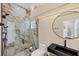 A bright bathroom with a walk-in shower and glass door, and a round mirror above the countertop at 5217 88Th E St, Bradenton, FL 34211