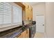 A modern laundry room features wood cabinetry, black hardware, sleek countertops, and stainless steel appliances at 5217 88Th E St, Bradenton, FL 34211