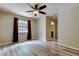 Bright bedroom with wood floors, ceiling fan, window with curtains, and a doorway to the ensuite bathroom at 8200 Westfield Dr, Port Richey, FL 34668