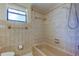 Shower over tub with beige tile, shower head, grab bars, and a window for natural light at 8200 Westfield Dr, Port Richey, FL 34668