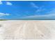 Expansive view of a pristine white sand beach under a clear blue sky with tire tracks in the sand at 880 Mandalay Ave # C512, Clearwater Beach, FL 33767