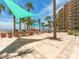 Outdoor common area featuring shade sails, dining tables, grilling stations, and tropical palm trees at 880 Mandalay Ave # C512, Clearwater Beach, FL 33767