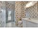 Cozy bathroom featuring a floral wallpaper, vanity, toilet, and glass-enclosed shower leading to the outdoors at 1216 Fox Chapel Dr, Lutz, FL 33549