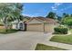 Spacious home with a three-car garage, a long driveway, and mature landscaping at 1216 Fox Chapel Dr, Lutz, FL 33549