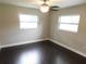 Comfortable bedroom with ceiling fan, two windows, and hardwood floors at 12417 N Rome Ave, Tampa, FL 33612