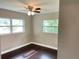 Clean bedroom with dark wood floors, two windows, and a ceiling fan at 12417 N Rome Ave, Tampa, FL 33612