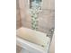 Close-up of a bathtub with stylish tile accent and a built-in niche for storage at 12417 N Rome Ave, Tampa, FL 33612