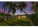 Backyard view with fenced-in yard, lush green grass, and mature landscaping, under a twilight sky at 1800 Mapleleaf Blvd, Oldsmar, FL 34677