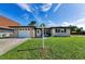 Charming single-story home with a well-manicured lawn, a white garage door and a welcoming front entrance at 1800 Mapleleaf Blvd, Oldsmar, FL 34677