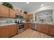 Modern kitchen with stainless steel appliances, warm wood cabinets, and a seamless view into the living area at 2349 Willimette Dr, Wesley Chapel, FL 33543