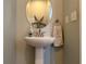 Powder room with a pedestal sink, round mirror, and decorative starfish adding coastal charm at 2349 Willimette Dr, Wesley Chapel, FL 33543