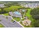 Aerial view of a clubhouse, playground, and pool surrounded by lush lawns, walking trails, and tropical plants at 2518 Chapel Oak Bnd, Wesley Chapel, FL 33543